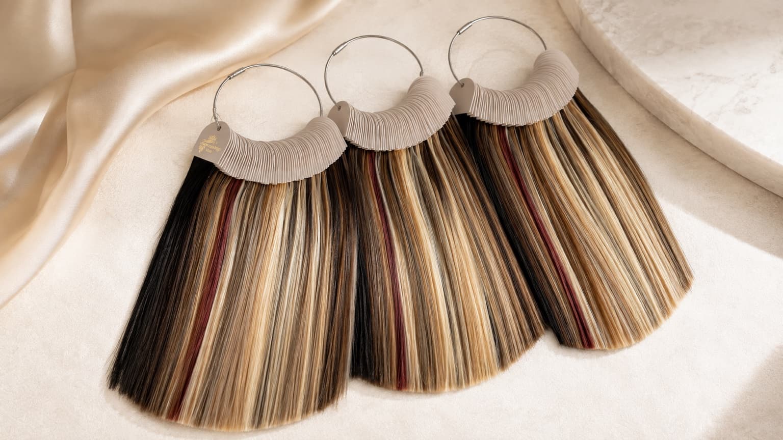 Three hair extension color rings displaying multiple human hair shades