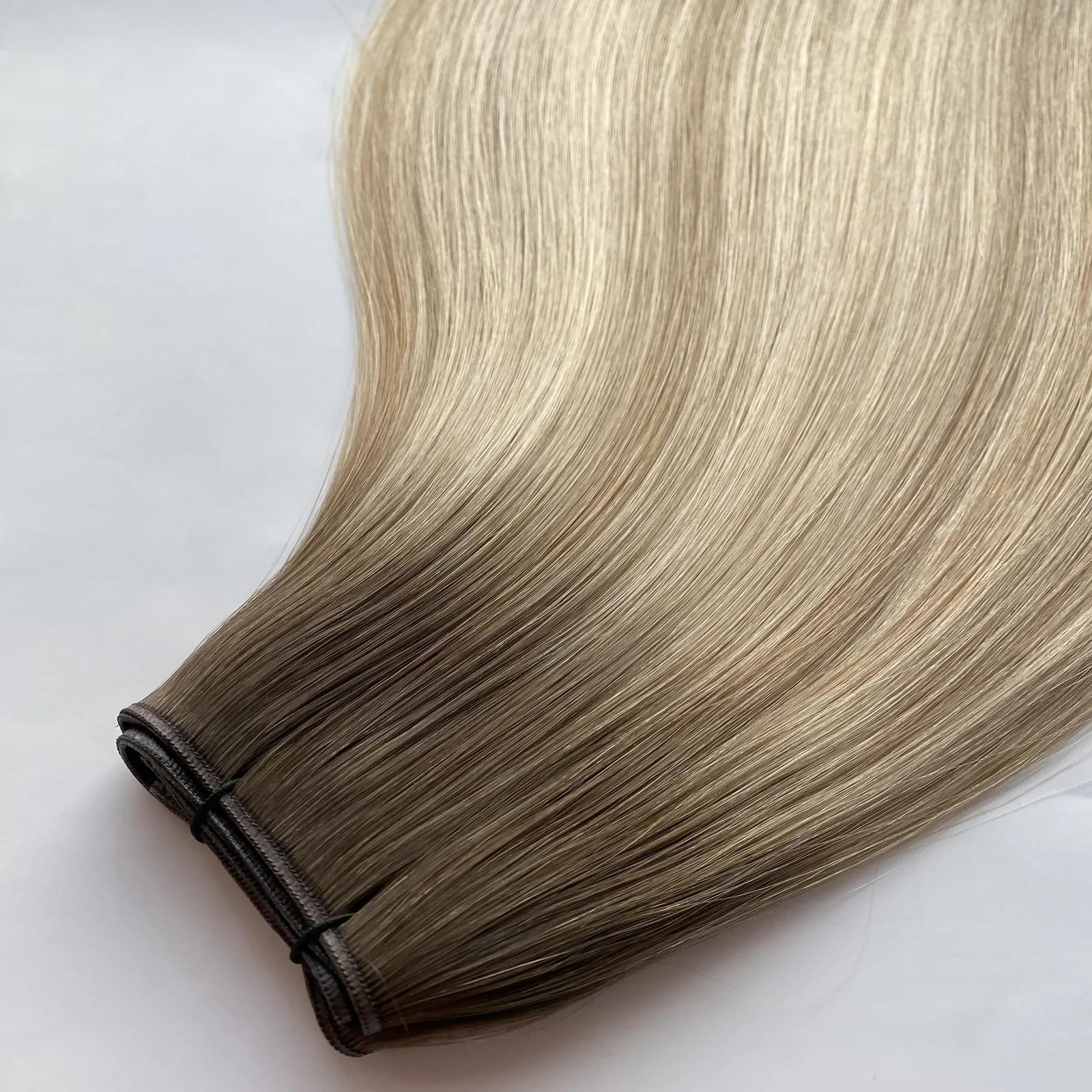 Rolled brown-to-blonde Volume Genius Weft showing the double-layer seam and straight hair